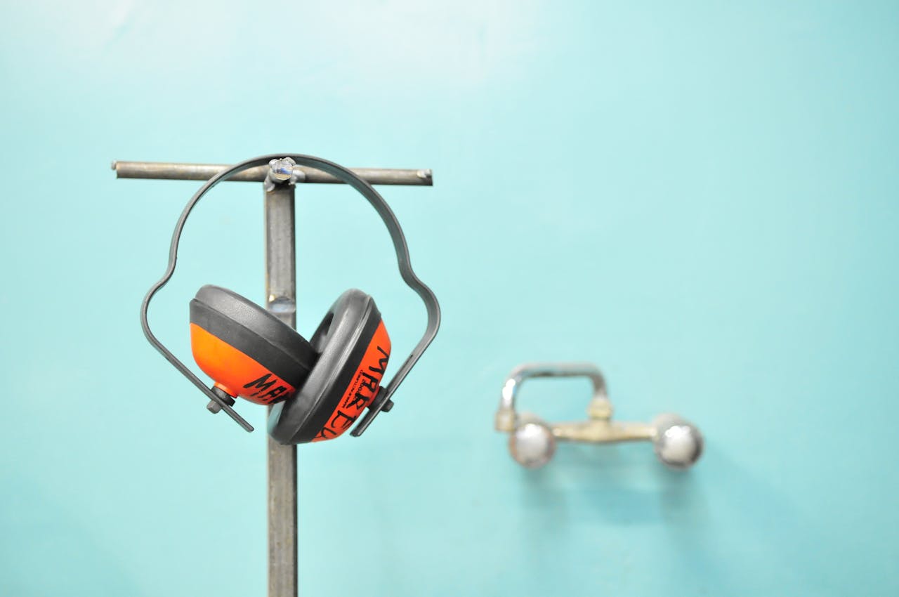 Services-03 Close-up of earmuffs hanging on a metal stand in front of a teal wall.